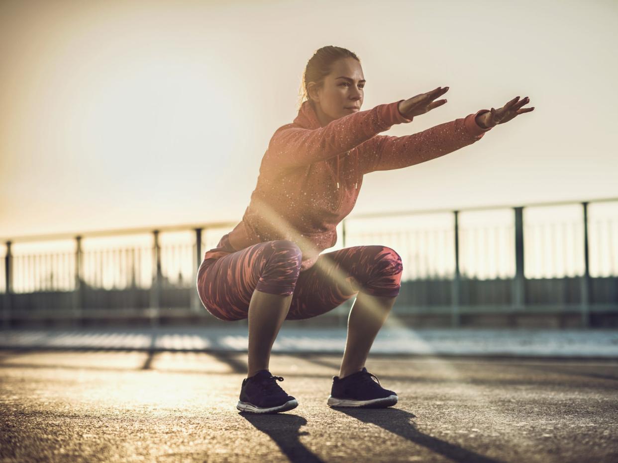 An athlete performing a bodyweight squat exercise outdoors