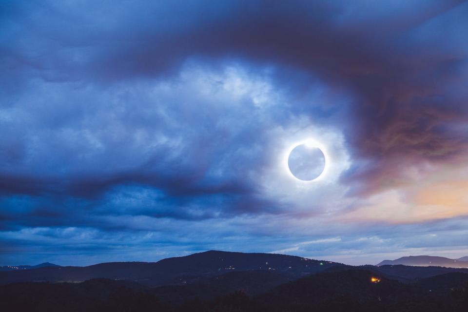 A total solar eclipse covered in purple clouds.