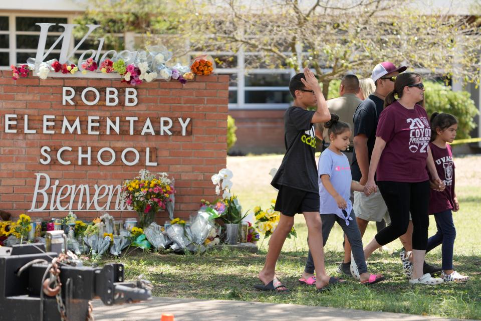 Visitors pay respects at the school sign of Robb Elementary School on the day after a mass shooting that left 19 children and two adults dead in Uvalde, Texas.