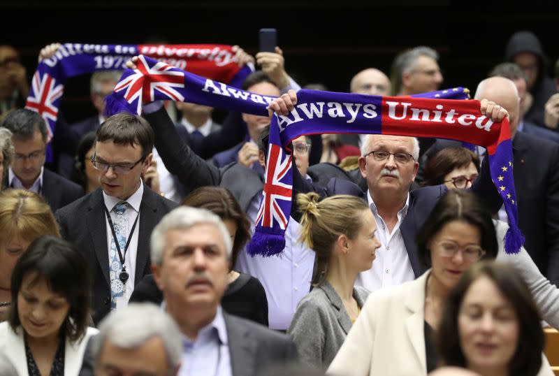 Members of the European Parliament react after voting on the Brexit deal during a plenary session at the European Parliament in Brussels