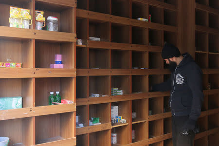 A pharmacist inspects low medical supplies inside a pharmacy in a rebel-held besieged area in Aleppo, Syria December 2, 2016. REUTERS/Abdalrhman Ismail