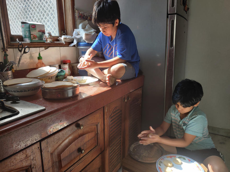 En esta imagen, tomada el 19 de abril de 2020 y proporcionada por Anil Sanweria, sus hijos Uddhav Pratap, de 8 años (izquierda), y Advait Vallabh, de 9, ayudan en la cocina durante la cuarentena por el coronavirus. Estos hermanos creen que el encierro debería continuar durante un año. “No deberían reabrir hasta que queden cero casos”, dice el más pequeño, Uddhav Pratap. (Anil Sanweria vía AP)