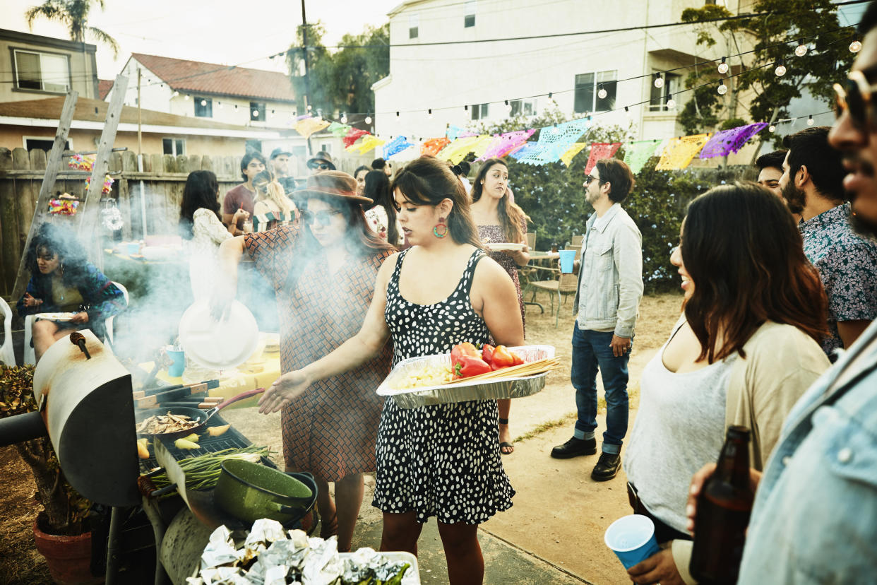 Women grilling food on barbecue during backyard party with friends
