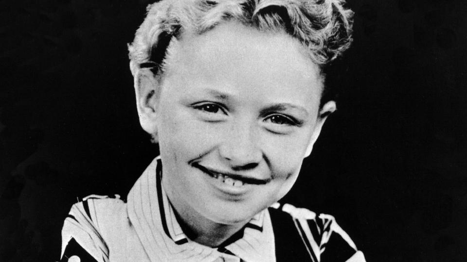 a black and white photo of a young dolly parton with her arms crossed, smiling at the camera