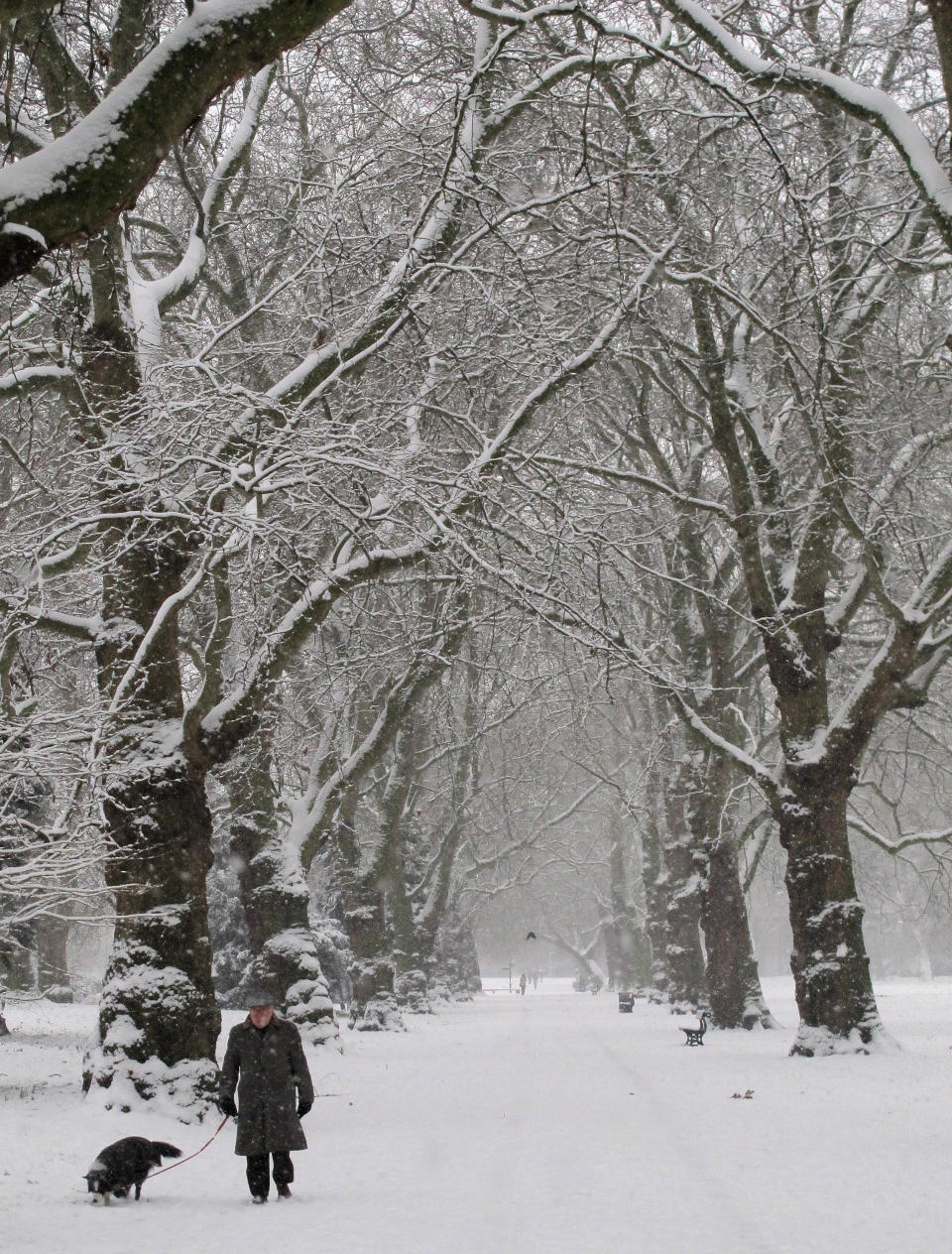 A man walks his dog through a snow covered park in south London, Sunday, Jan. 20, 2013. The big freeze across Britain is here to stay, with more snow expected next week. (AP Photo/Tony Hicks)