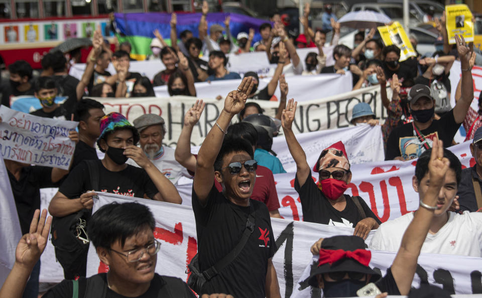 Activist Jatupat Boonpattararaksa, front center, raises a three-finger salute, a symbol of resistance, with anti-government protesters before he turns up at Samranrat police station in Bangkok, Thailand, Friday, Aug, 28, 2020. Anti-government protesters tussled with police on Friday as 15 of their movement leaders turned up at a police station to answer a summons linked to demonstrations denouncing the arrests. (AP Photo/Sakchai Lalit)