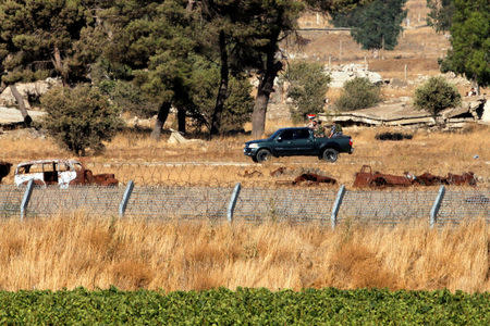 Uniformed men ride a pick-up truck as they carry a Syrian flag in Quneitra on the Syrian side of the ceasefire line between Israel and Syria, as seen from the Israeli-occupied Golan Heights, July 26, 2018. REUTERS/Ammar Awad