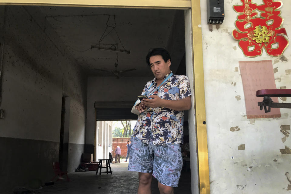 In this July 12, 2018, photo, Li Qinggong stands outside the entrance to this home in Gucheng village in central China's Henan province. The AP spoke to the family Marip Lu, a young woman from Myanmar, accused of abusing her. The father, Li Qinggong, and mother, Xu Ying, both denied Marip Lu had been abused or raped, and insisted she had not been purchased. But neither was able to explain how she'd ended up in their faraway village, or how she allegedly met and "married" their mentally disabled son, Li Mingming. (AP Photo/Ng Han Guan)