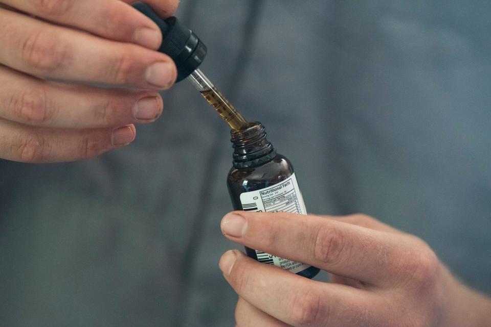 Benjamin Bramlett of Sustainable CBD shows a CBD tincture at Neal Pope Farms in Salem, Alabama, on July 27, 2022.