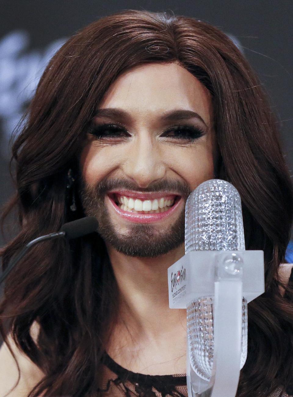 Singer Conchita Wurst representing Austria who performed the song 'Rise Like a Phoenix' smile as she sits by the trophy during a press conference after winning the Eurovision Song Contest in the B&W Halls in Copenhagen, Denmark, Saturday, May 10, 2014.(AP Photo/Frank Augstein)