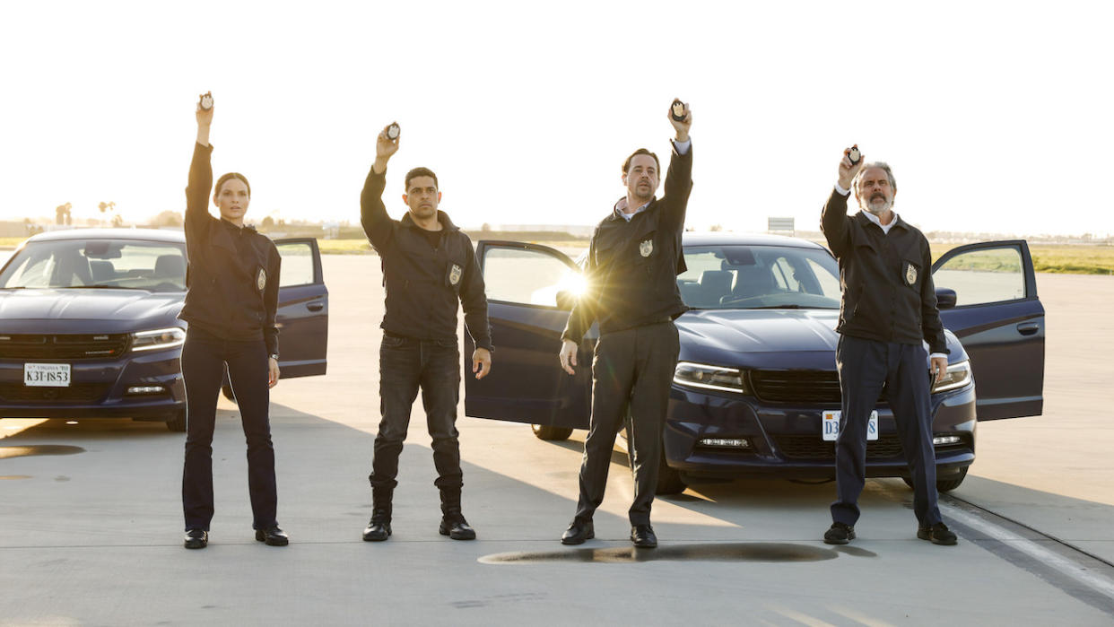  Katrina Law, Wilmer Valderrama, Sean Murray and Gary Cole holding up badges in NCIS. 