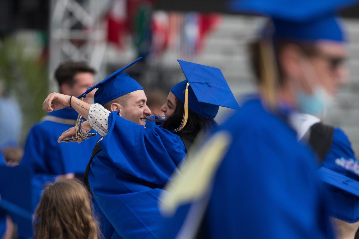 University of Delaware students embrace during the 2021 commencement ceremony at Delaware Stadium in Newark.