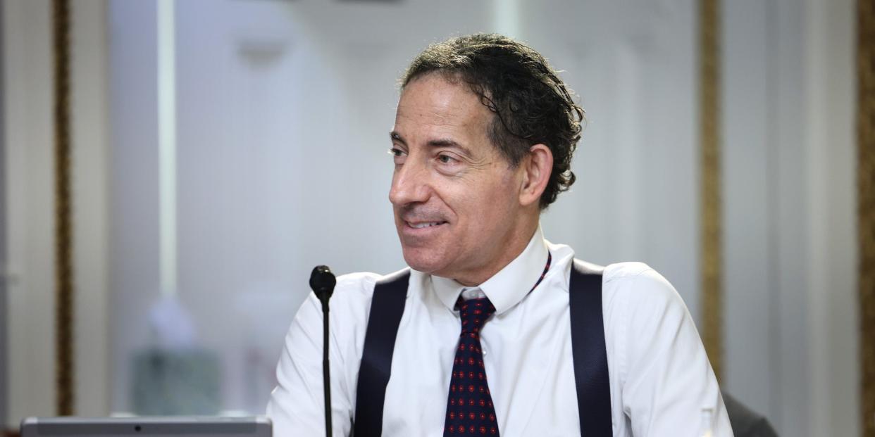 Congressman Jamie Raskin sits behind a podium wearing a white shirt, black suspenders and a black tie.