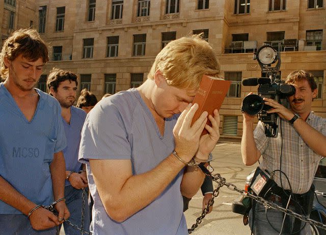 <p>Chad Surmick/AP</p> Heber LeBaron covers his face with a bible while he and his half brother Douglas Barlow leave a preliminary extradition hearing at the Justice Court in Phoenix, AZ on July 18, 1988.