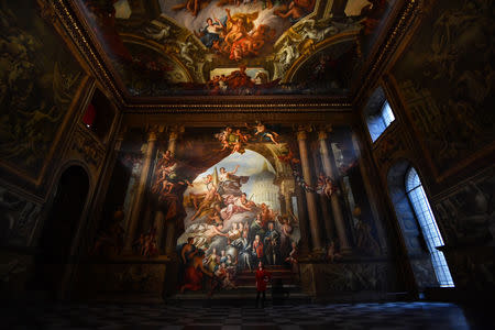 A gallery assistant poses beside a fresco during the reopening of The Painted Hall, Old Royal Navy College in London, Britain, March 20, 2019. REUTERS/Dylan Martinez