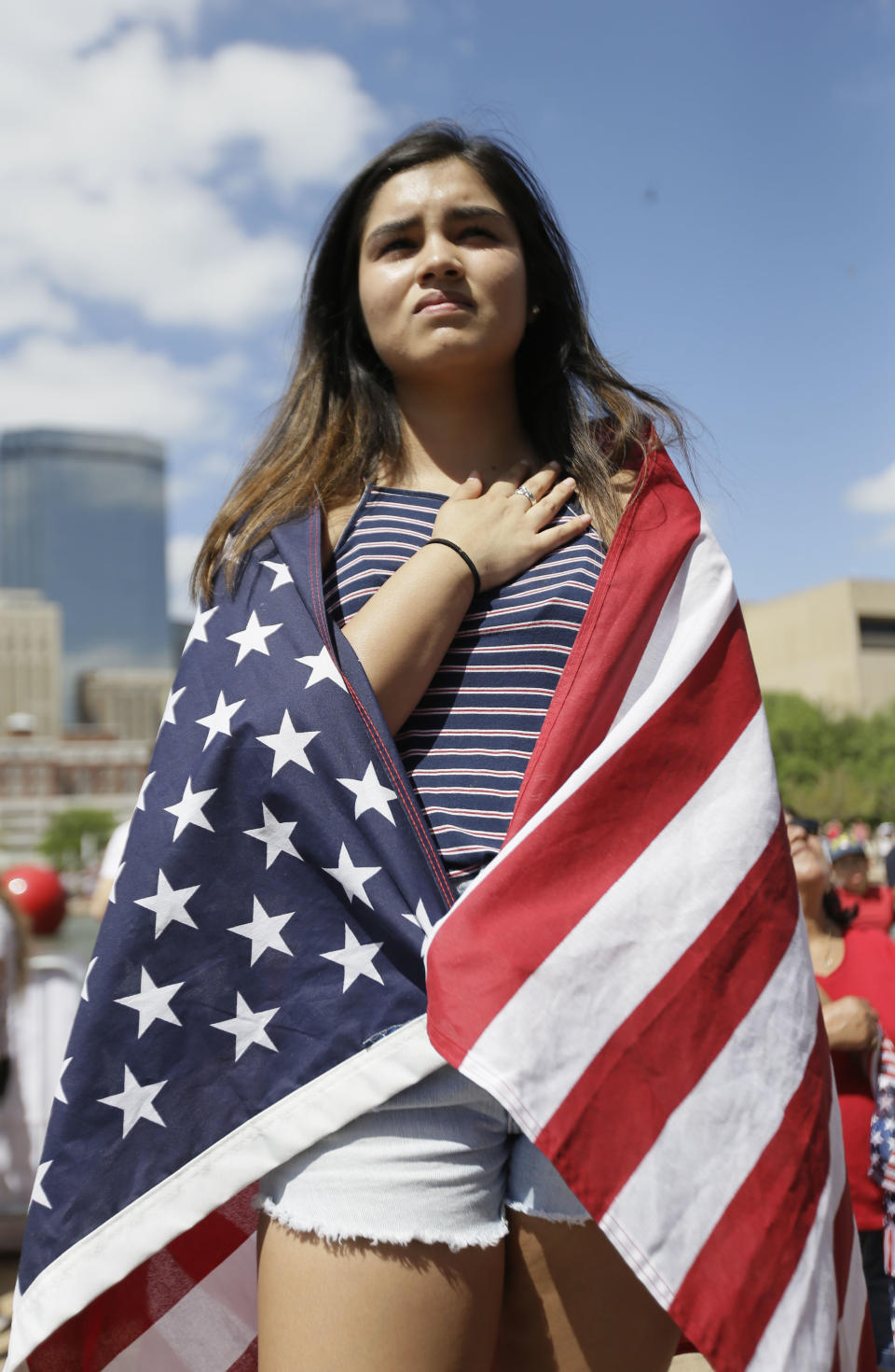 High school student Leslie Bonilla, 17, stands during the national anthem as protestors rally in downtown Dallas, Sunday, April 9, 2017. Thousands of people are marching and rallying in downtown Dallas to call for an overhaul of the nation's immigration system and end to what organizers say is an aggressive deportation policy. (AP Photo/LM Otero)