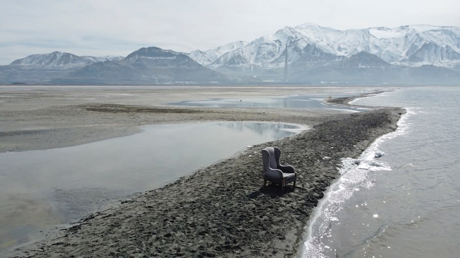 A chair sits on an exposed sand bar on the southern shore of the Great Salt Lake with mountains viewable in the background
