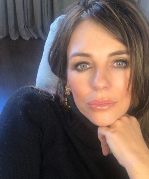A photo of Liz Hurley wearing a black turtleneck jumper and pink lipgloss.