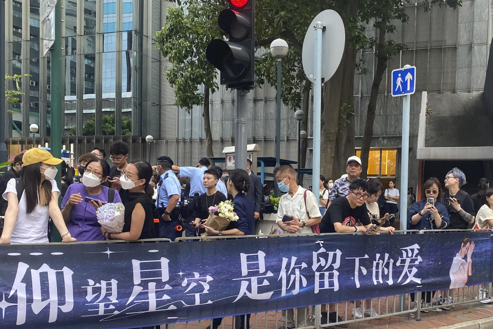 Fans gather near a banner which reads "Looking up at the starry sky, it is the love you left behind" outside the Hong Kong Funeral HHome, where a funeral is set up for Hong Kong singer and songwriter Coco Lee, in Hong Kong on Monday, July 31, 2023. Fans of singer and songwriter Coco Lee, who was known for her powerful voice and live performances, were gathering with flowers to pay their respects at her funeral in Hong Kong. (AP Photo/Annie Cheung)