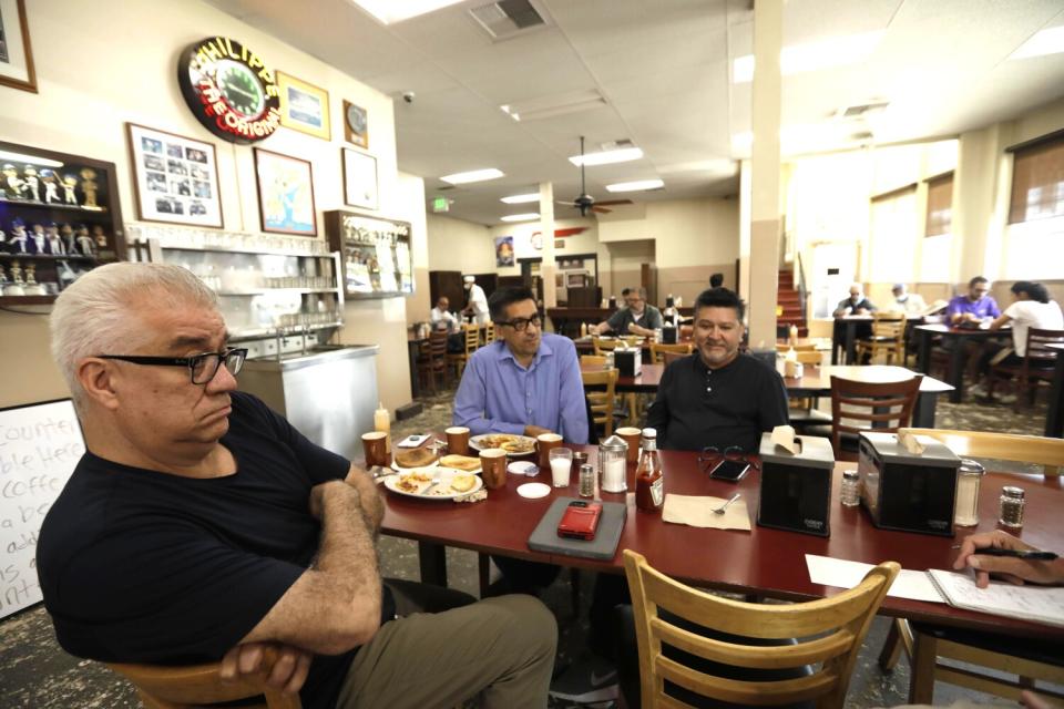 Three men sit at a table in a restaurant