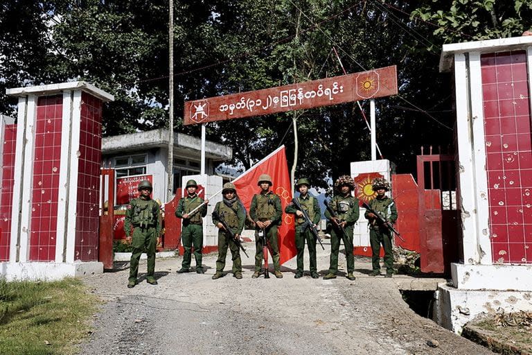Miembros del Ejército de la Alianza Democrática Nacional de Myanmar posan para una fotografía delante del batallón de infantería del ejército incautado en el municipio de Kunlong, en el estado de Shan, Myanmar, el domingo 12 de noviembre de 2023.
