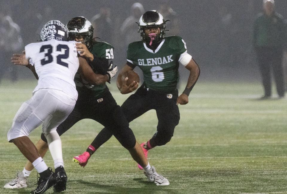 GlenOak’s Avantae Burt cuts behind the blocking of Ashton Rulewicz (59) on Lorain’s Avery Martin on Friday, Oct. 27, 2023.