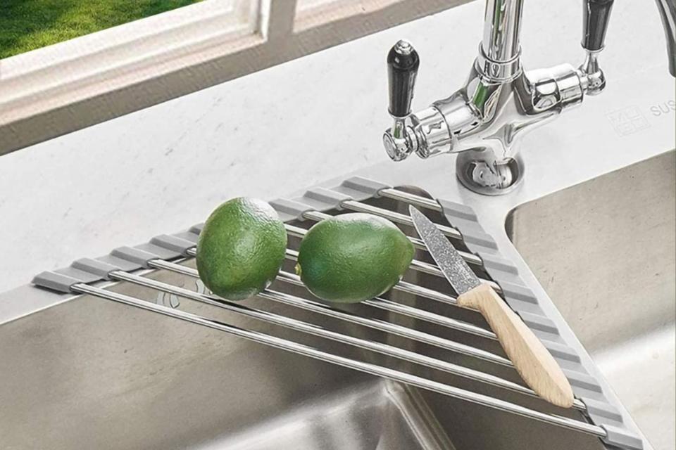 Drying rack at the sink corner holding two limes and a paring knife.