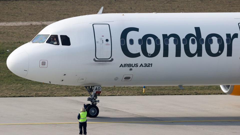 Der Pilot einer Condor-Maschine mit Ziel Teneriffa winkt dem Bodenpersonal vor dem Start vom Flughafen Leipzig/Halle.