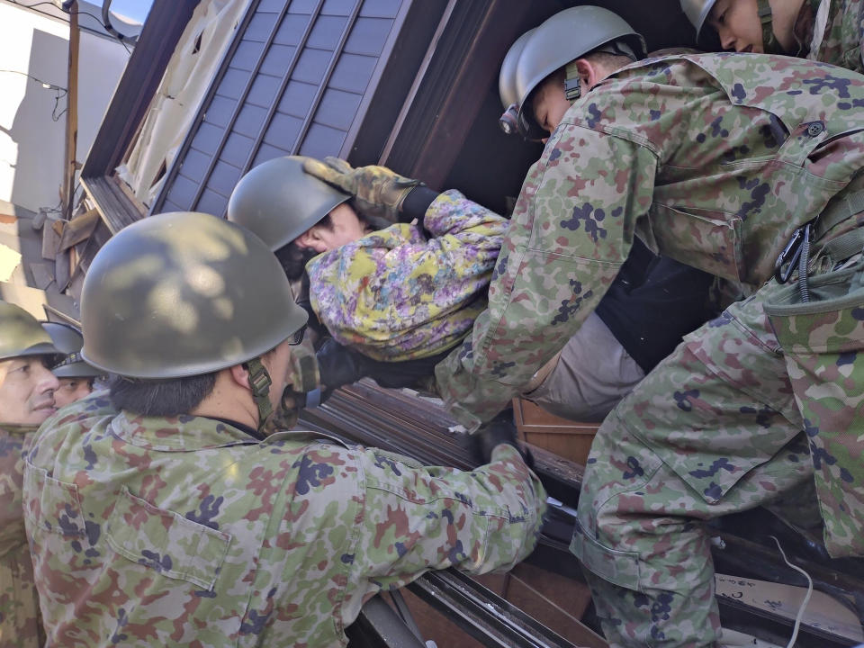 In this photo provided by Japanese Ministry of Defense, Japanese Self Defense Force members carry an injured person out of a collapsed house, following strong earthquakes in Wajima, Ishikawa prefecture, Japan, Tuesday, Jan. 2, 2024. (Japanese Ministry of Defense via AP)