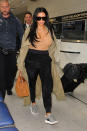 If your airplane wardrobe involves worn-in leggings and an old T-shirt, then be prepared to be upstaged by Kim. During a trip through LAX, she re-wore the aforementioned bodysuit, this time with a pair of silky black pants, heels and a long olive trench.