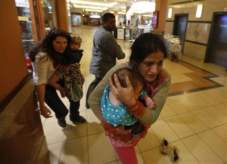 Women carrying children run for safety as armed police hunt gunmen who went on a shooting spree in Westgate shopping centre in Nairobi September 21, 2013. REUTERS/Goran Tomasevic