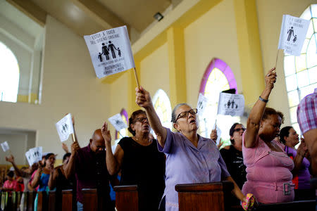 Worshippers wave paper flags that read in Spanish "I am in favour of the original design. The family as God created it. Wedding between man and woman", during a service at a Methodist Church in Havana, Cuba, October 4, 2018. REUTERS/Alexandre Meneghini