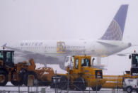 A United Airlines jetliner is sprayed with de-icing fluid while passing by a line of snow removal equipment on the way to a runway as a winter storm sweeps over the intermountain West Tuesday, Jan. 26, 2021, at Denver International Airport in Denver. Forecasters predict that the fast-moving storm could leave up to a foot of snow in some parts of the region before giving way to a front packing warmer temperatures for the rest of the week. (AP Photo/David Zalubowski)