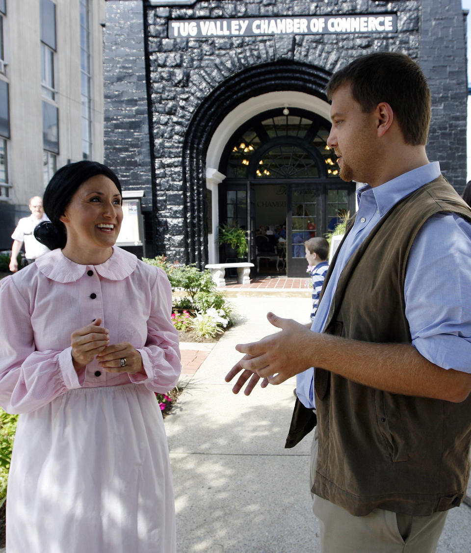 In this Saturday, June 9, 2012 photo, Barry Hatfield, right, dressed as Johnse Hatfield and Lynee Starr, left, as Roseanna McCoy discuss the history of the Hatfield-McCoy feud in front of the Coal House during the Hatfield-McCoy Reunion in Williamson, W.V. (AP Photo/ James Crisp)