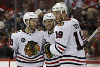 Chicago Blackhawks left wing Alex DeBrincat, center, celebrates with teammates after scoring a goal against the New Jersey Devils during the second period of an NHL hockey game Friday, Oct. 15, 2021, in Newark, N.J. (AP Photo/Adam Hunger)