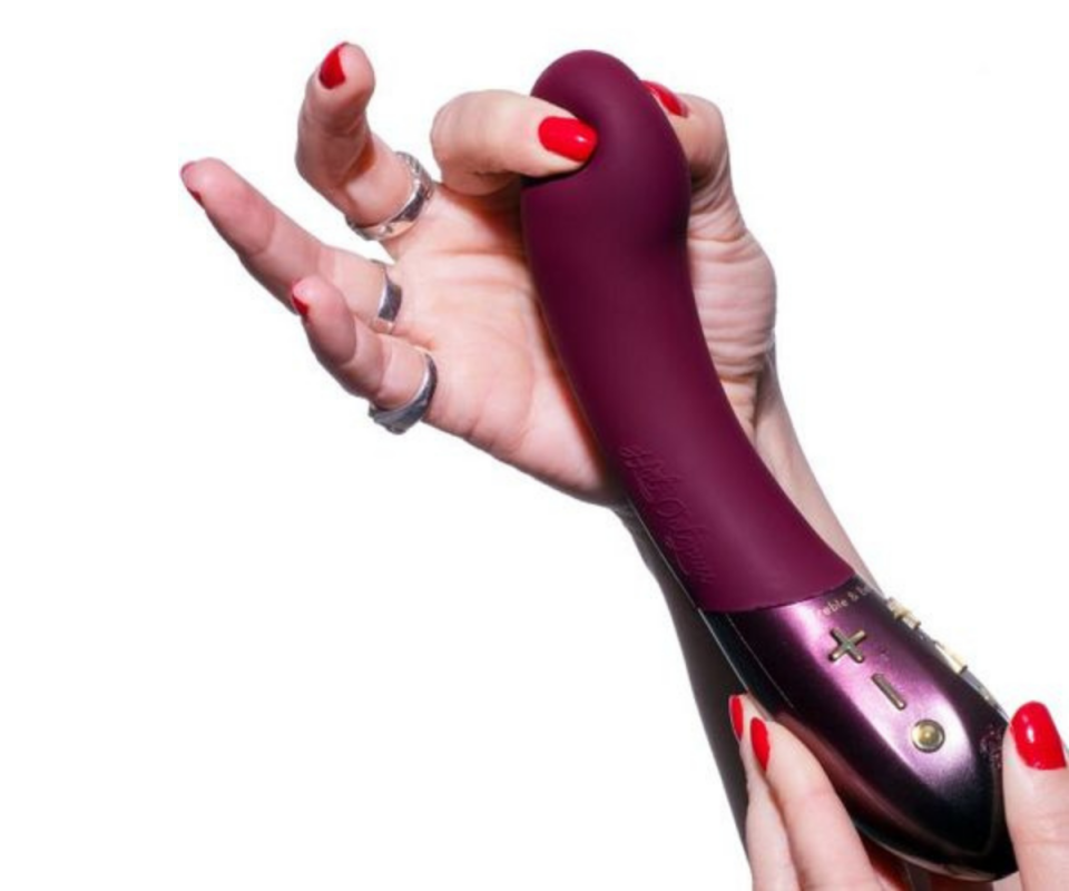 Female hands with red nails holding a maroon silicone enclosed Kurve G-Spot vibrator