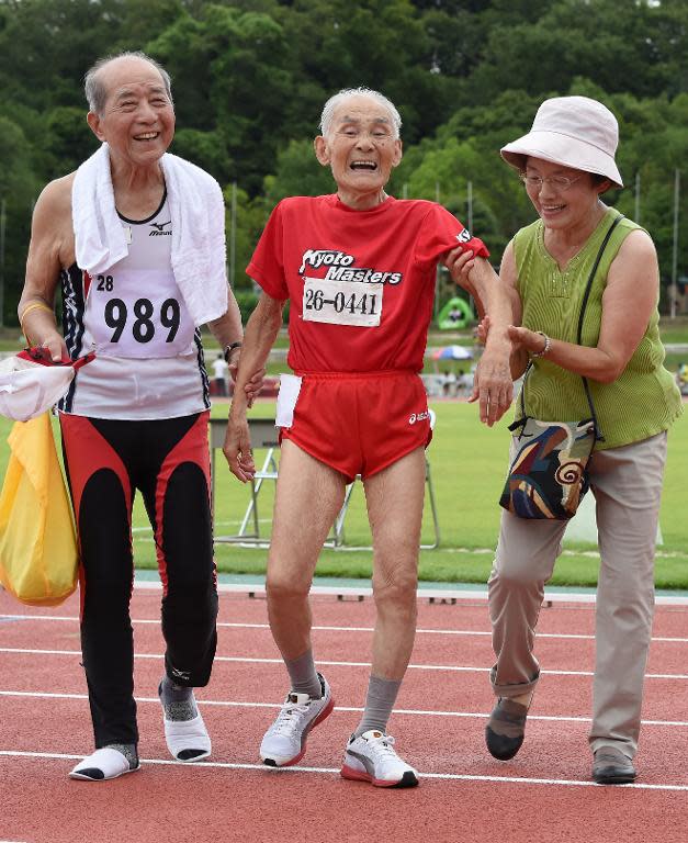 103-year-old sprinter Hidekichi Miyazaki (C) is helped by his daughter Kiyono (R) and a fellow athlete after crossing the finish line at a race in Kyoto on August 3, 2014