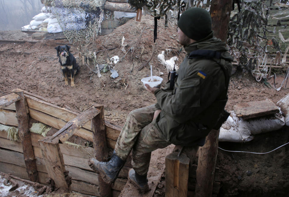 A Ukrainian soldier eats in a trench in the front line near the town of Novoluhanske in the Donetsk region, Ukraine, Monday, Dec. 9, 2019. A long-awaited summit in Paris on Monday aims to find a way to end the war in eastern Ukraine, a conflict that after five years and 14,000 lives lost has emboldened the Kremlin and reshaped European geopolitics. (AP Photo/Vitali Komar)