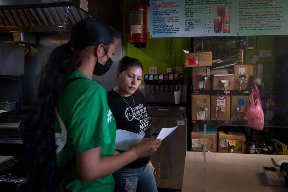 Melissa López explica el proceso de prueba de covid a un empleado de una taquería en Fresno, California, como parte de su capacitación como educadora de salud. Foto Heidi de Marco/KHN/(Heidi de Marco/KHN)
