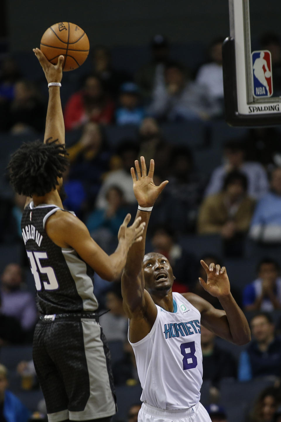 Sacramento Kings forward Marvin Bagley III, left, shoots over Charlotte Hornets center Bismack Biyombo in the first half of an NBA basketball game in Charlotte, N.C., Tuesday, Dec. 17, 2019. (AP Photo/Nell Redmond)