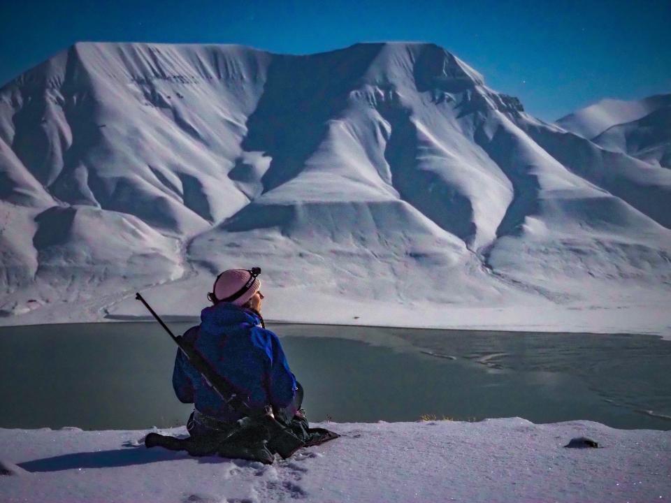 The writer sits across from a snow-covered mountain and a frozen lake