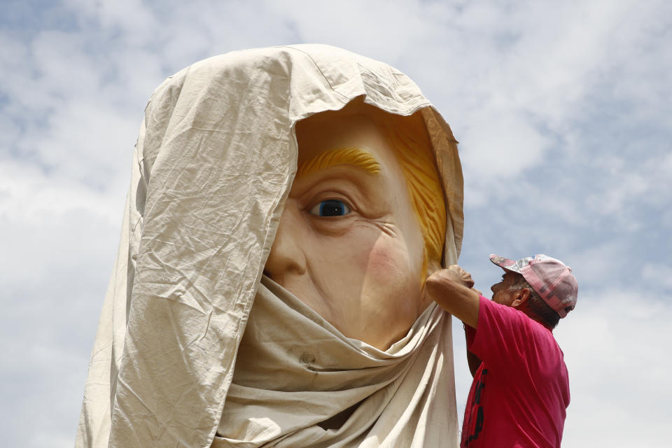 A protester unwraps a sculpture depicting President Donald Trump holding a cell phone on a toilet before Independence Day celebrations, Thursday, July 4, 2019, on the National Mall in Washington. (AP Photo/Patrick Semansky)