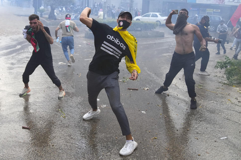 Protesters throw stones towards riot police, during a demonstration in solidarity with the Palestinian people in Gaza, near the U.S. embassy in Aukar, a northern suburb of Beirut, Lebanon, Wednesday, Oct. 18, 2023. Hundreds of angry protesters are clashing with Lebanese security forces in the Lebanese suburb Aukar near the United States Embassy. (AP Photo/Bilal Hussein)