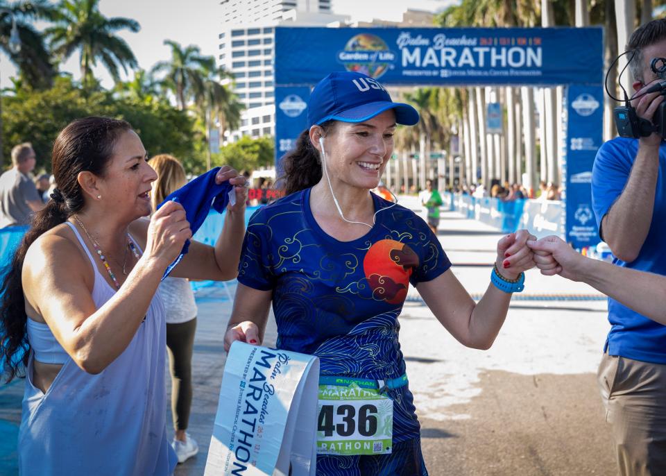 Katalin Nagy gets a fist bump after winning the women's division of The Garden of Life Palm Beaches Marathon on Flagler Drive in West Palm Beach, Florida on December 12, 2021.