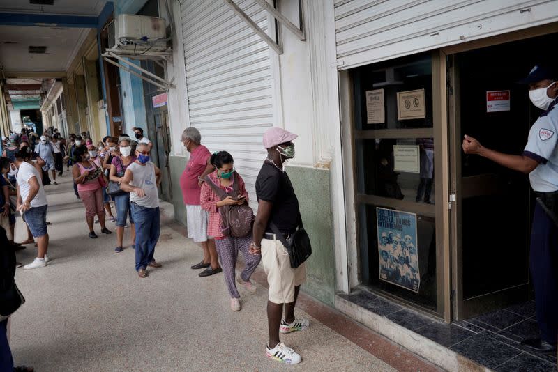 FILE PHOTO: People wait in line to enter a currency exchange office in Havana, Cuba