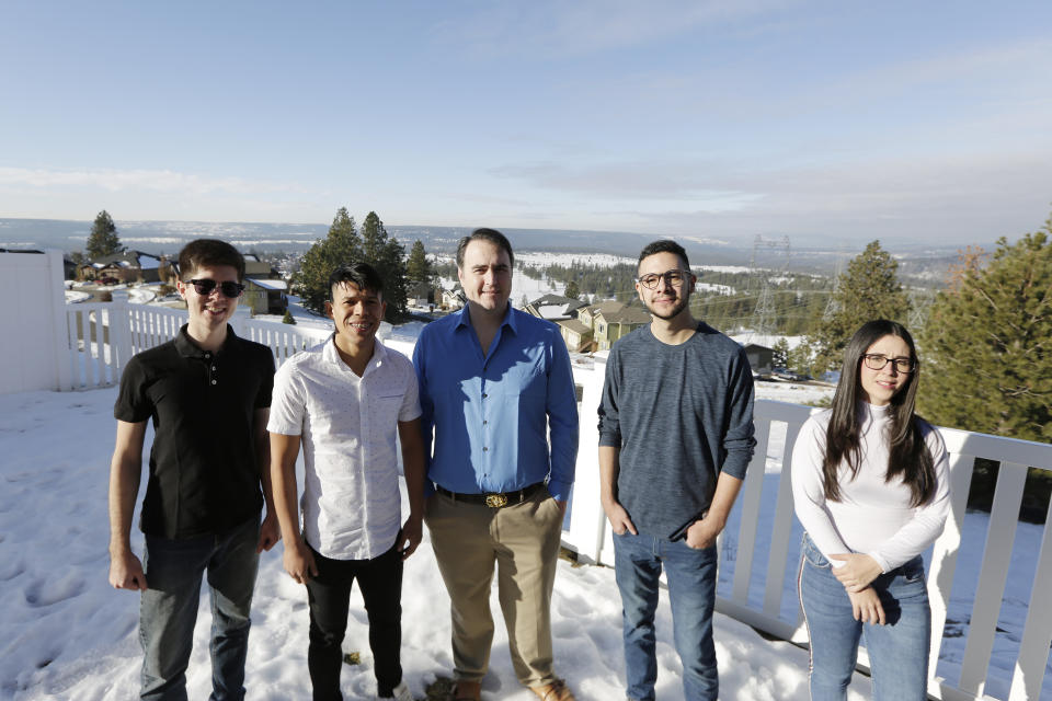 Dr. Kyle Varner, center, who sponsors and houses people through the Venezuelan humanitarian parole program, poses for a photograph at his house with program beneficiaries, from left, Cesar Baez, Jenderson Rondon, Henry Nadales and Maria Amare, Friday, Jan. 6, 2023, in Spokane, Wash. (AP Photo/Young Kwak)
