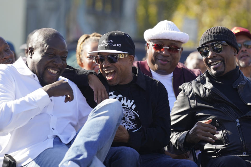 From left, Ray Luv, Money-B, E-40 and MC Hammer laugh during a street renaming ceremony for Tupac Shakur in Oakland, Calif., Friday, Nov. 3, 2023. A stretch of street in Oakland was renamed for Shakur, 27 years after the killing of the hip-hop luminary. A section of Macarthur Boulevard near where he lived in the 1990s is now Tupac Shakur Way, after a ceremony that included his family members and Oakland native MC Hammer. (AP Photo/Eric Risberg)