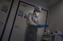 A Belgian Army medic suits up as she prepares to bring lunch to a patient with COVID-19 at the St. Michiel Hospital in Brussels, Tuesday, Nov. 24, 2020. The Belgian military has been called into several hospitals and care homes to alleviate the stress on healthcare personnel. (AP Photo/Virginia Mayo)