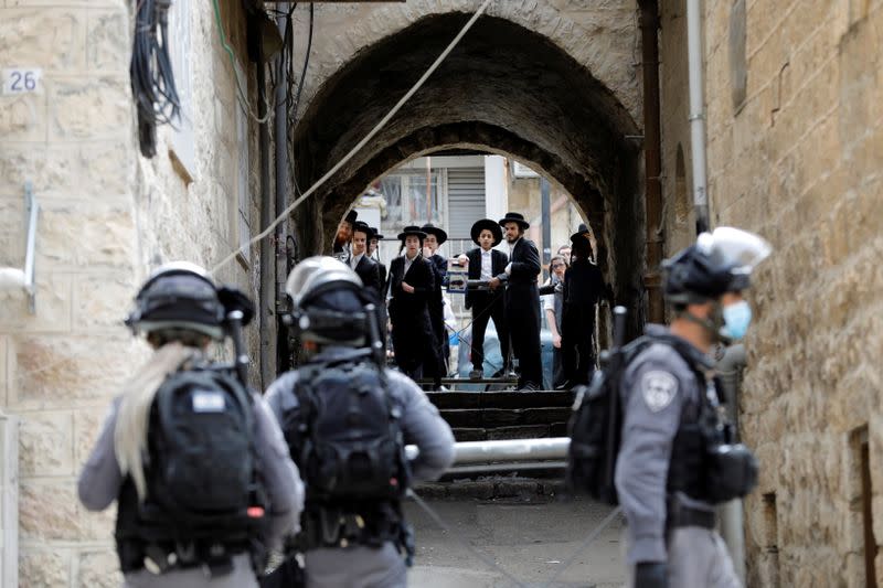 Ultra-Orthodox Jewish youths look at Israeli police as they patrol to enforce restrictions of a partial lockdown against the coronavirus disease (COVID-19) in Mea Shearim neighbourhood of Jerusalem