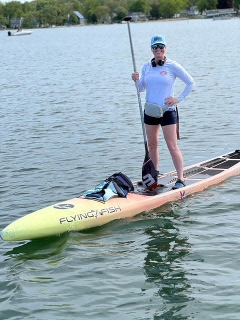 Kim Iasielo of Burlington stands on the paddleboard she plans to use in The Crossing for Cystic Fibrosis, later in June.